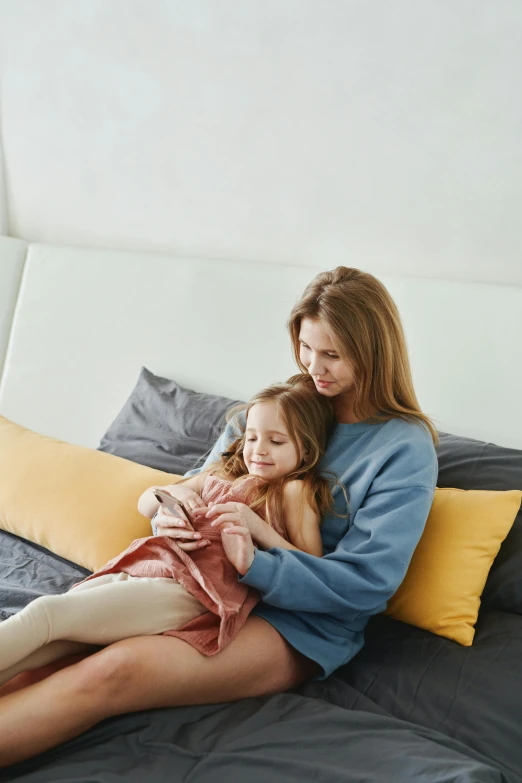 a woman sitting on top of a bed next to a little girl, connectivity, sitting on a couch, slate, uploaded