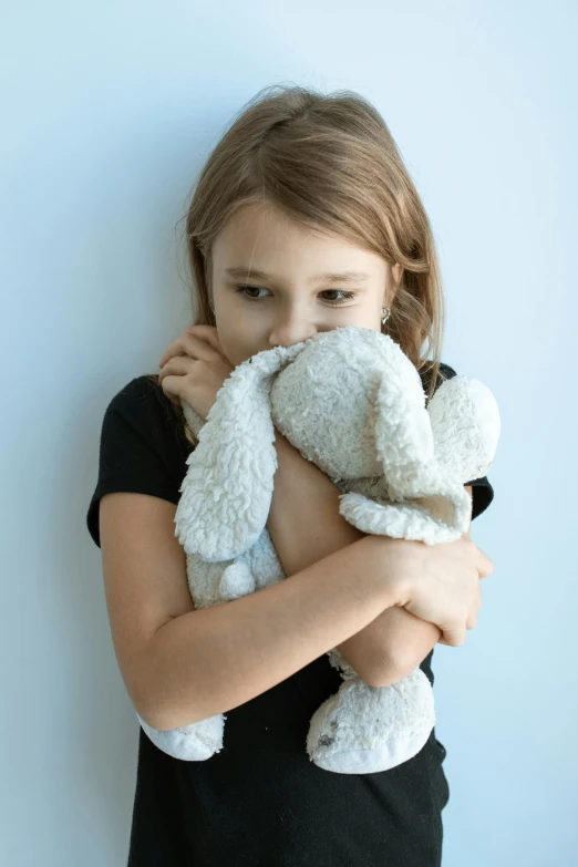 a little girl holding a stuffed animal in her hands, woman crying, arm around her neck, grey, trauma