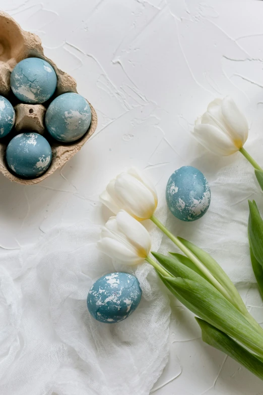 blue and white easter eggs and tulips on a white table, trending on unsplash, baroque, distressed paint, embedded with gemstones, grey, product display photograph