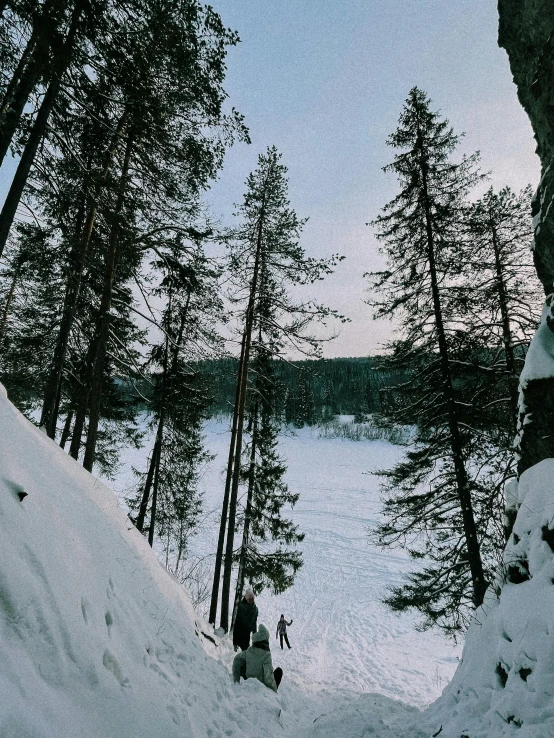 a group of people riding skis down a snow covered slope, lake in the forest, stalactites, kalevala, forest and river