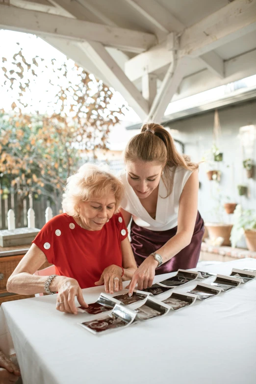 a woman standing next to a woman sitting at a table, pexels contest winner, process art, chocolate, inspect in inventory image, elderly, gardening