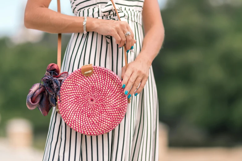 a woman in a striped dress holding a straw bag, a picture, by Julia Pishtar, unsplash, happening, wearing pink floral chiton, round-cropped, closeup - view, sarong