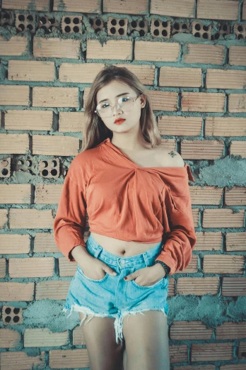a woman standing in front of a brick wall, inspired by Elsa Bleda, pexels contest winner, wearing an orange t shirt, ulzzang, croptop, 15081959 21121991 01012000 4k