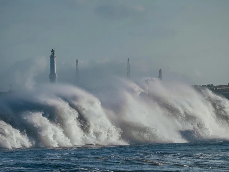 a large body of water with a lighthouse in the background, pexels contest winner, romanticism, turbulent waves, turbines, hull, flooding