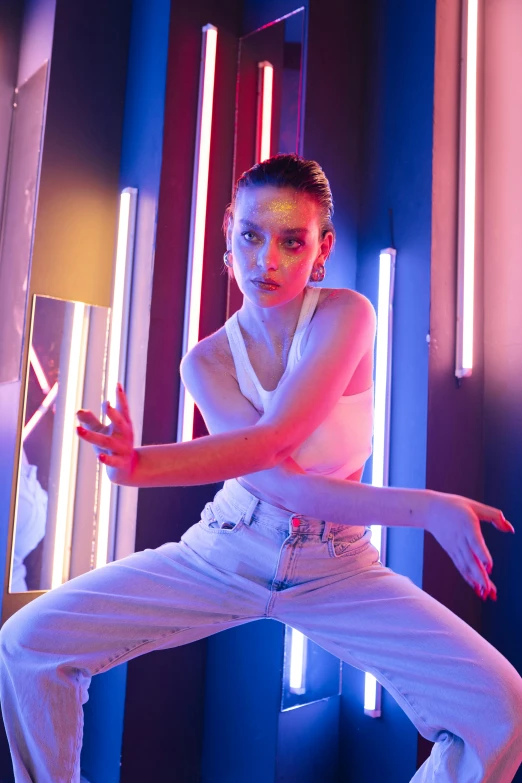 a woman in a white shirt and white pants, inspired by David LaChapelle, pexels contest winner, bauhaus, dilraba dilmurat, red and blue lighting, classic dancer striking a pose, natalia dyer