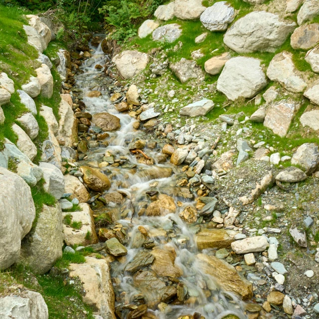 a stream running through a lush green hillside, by Julia Pishtar, pexels contest winner, hurufiyya, many small stones, uttarakhand, concert, whistler