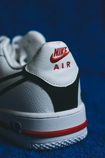 a close up of a pair of shoes on a blue surface, red white and black, air force, size 1 0, in white lettering
