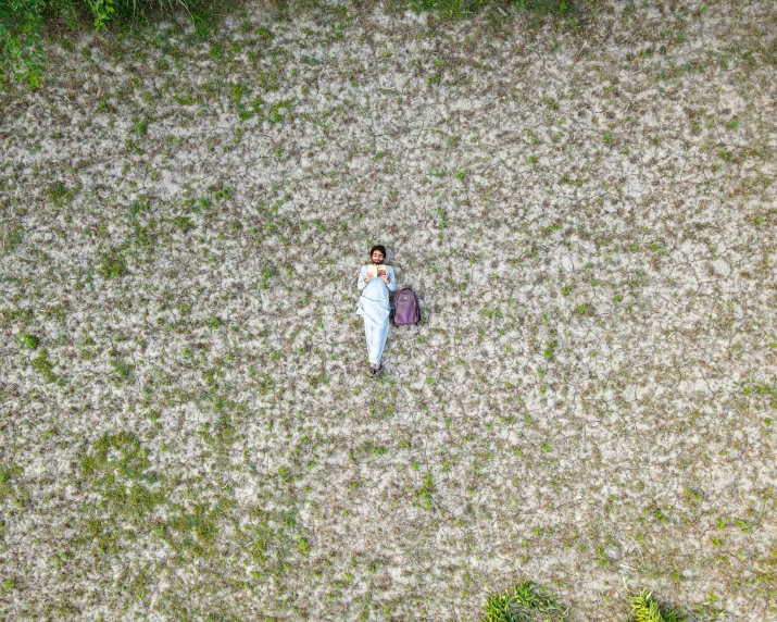 a woman laying in the middle of a field, by Sunil Das, pexels contest winner, conceptual art, helicopter view, walking down, movie still of a tired, top down perspecrive