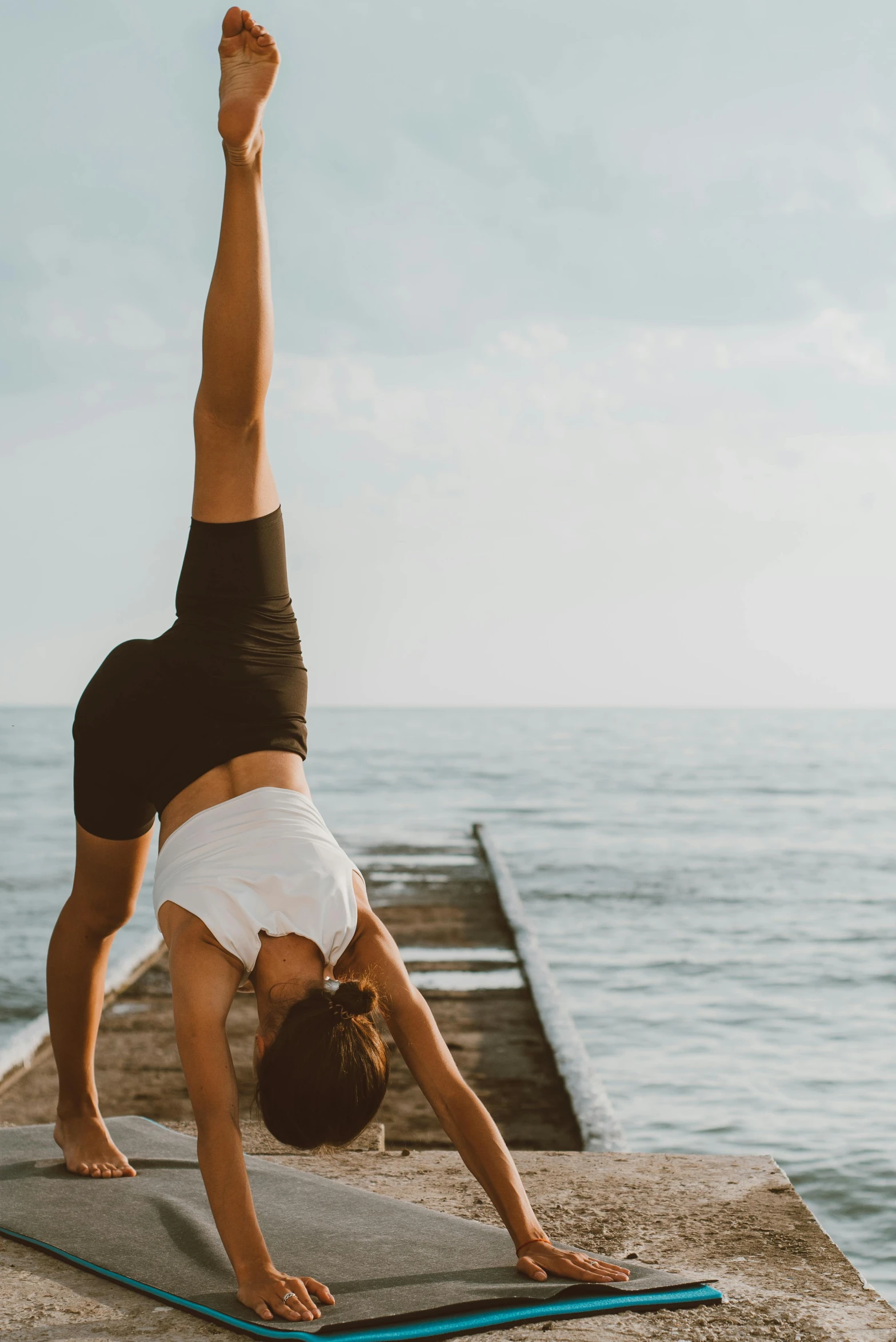 a woman doing a handstand on a yoga mat, pexels contest winner, arabesque, looking at the ocean, head tilted downward, cottagecore!! fitness body, man standing in defensive pose