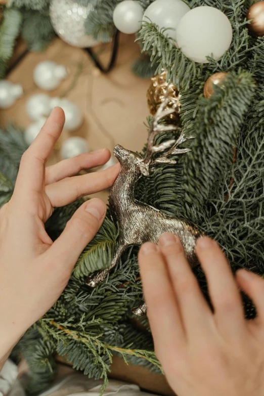 a person decorating a christmas tree with ornaments, short antlers, silver filigree details, 🦑 design, extremely lifelike