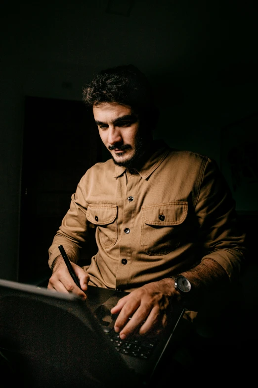 a man sitting in front of a laptop computer, by Alejandro Obregón, pexels contest winner, serial art, with trimmed mustache, on dark paper, indian, brown