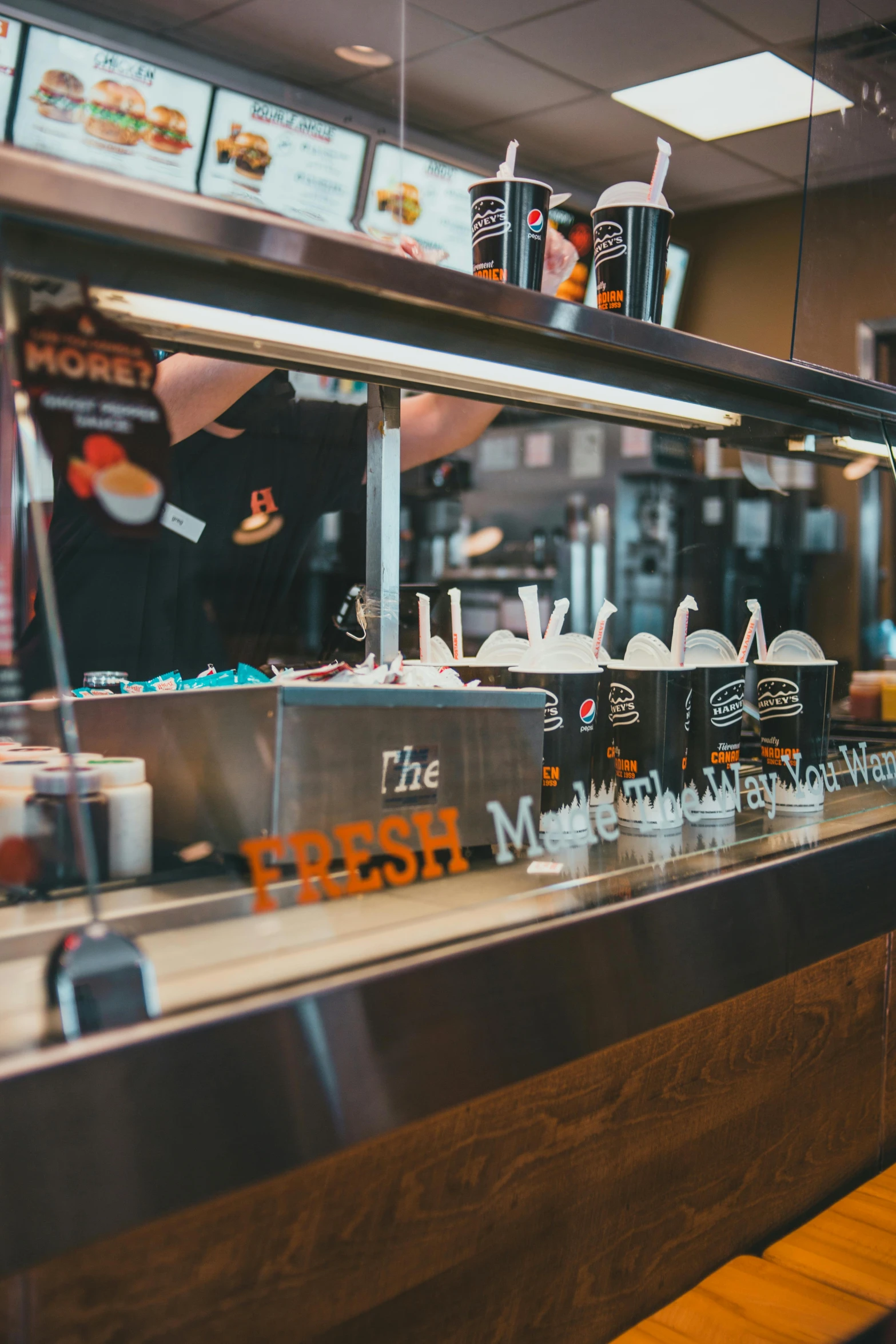 a man standing in front of a counter at a fast food restaurant, by Matthias Stom, pexels, graffiti, robots queue up for ice cream, moody morning light, background image, celebration of coffee products