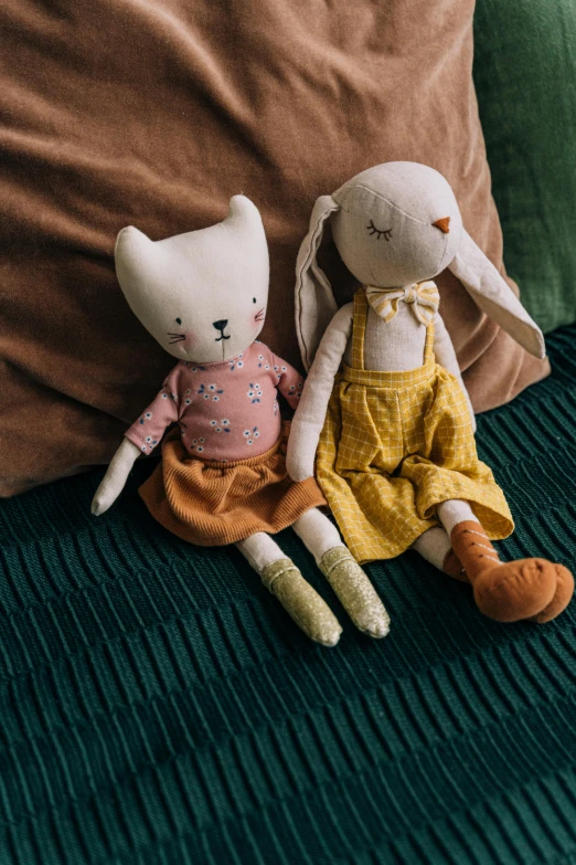 two stuffed animals sitting next to each other on a couch, inspired by Elsa Beskow, renaissance, high quality product photo, warm cosy colors, overalls, in her room