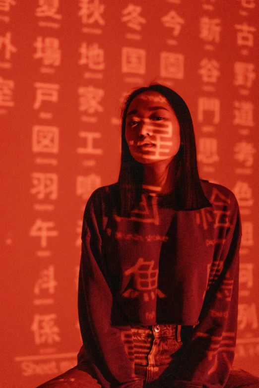 a woman sitting in front of a red wall, inspired by Li Di, trending on unsplash, conceptual art, kanji, light show, wearing red attire, fzd school of design