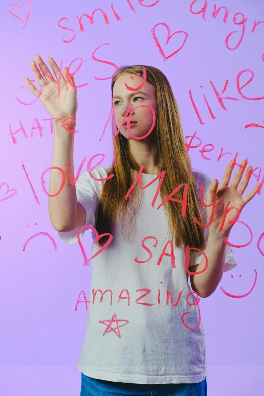 a woman standing in front of a wall with writing on it, inspired by Peter Alexander Hay, trending on pexels, aestheticism, sadie sink, hand gestures, bullying, pink and purple