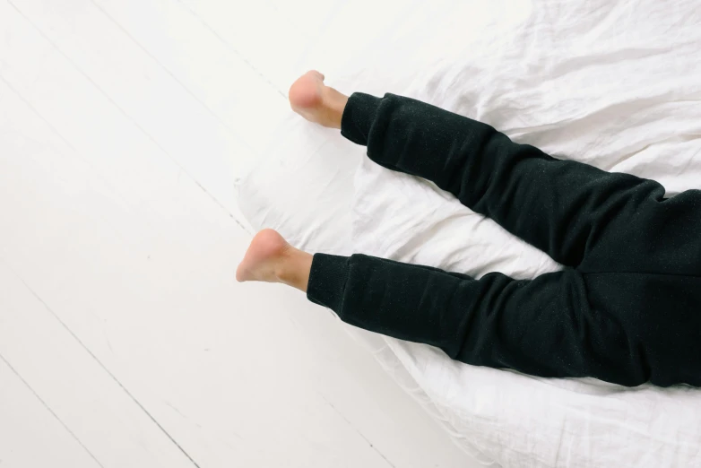 a close up of a person laying on a bed, minimalism, leggings, white and black clothing, stressing out, full body hero