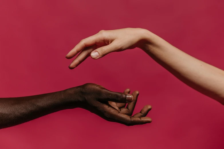 two hands reaching for each other on a red background, a black and white photo, by Arabella Rankin, trending on pexels, brown and pink color scheme, mix of ethnicities and genders, with grey skin, maxim sukharev