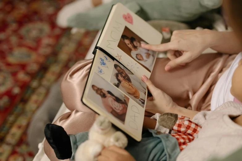 a woman is reading a book to a baby, a polaroid photo, by Julia Pishtar, pexels, reading for a party, avatar image, high angle close up shot, group photo