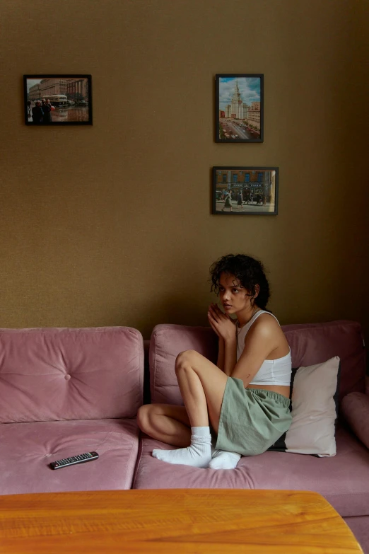 a woman sitting on a couch in a living room, inspired by Nan Goldin, pexels contest winner, visual art, bra and shorts streetwear, nathalie emmanuel, dafne keen, pink hue