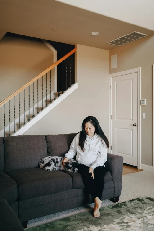 a woman sitting on a couch in a living room, by Marshall Arisman, unsplash, staircases, puppies, half asian, seattle