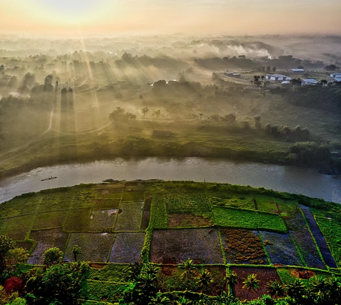 a hot air balloon flying over a lush green field, a matte painting, by Basuki Abdullah, pexels contest winner, sumatraism, foggy sunset, terraced orchards and ponds, view from helicopter, panoramic