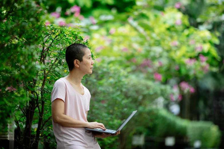 a man sitting on a bench with a laptop, by Shen Che-Tsai, happening, vibrant greenery outside, profile image, asian female, portrait image