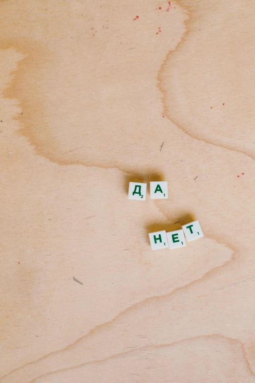 a couple of letters sitting on top of a wooden table, by Emma Andijewska, trending on pexels, letterism, russian academic, concrete poetry, a green, lada