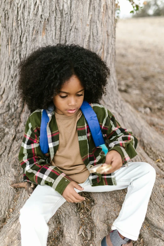 a little boy that is sitting on a tree, trending on pexels, long afro hair, having a snack, plaid shirt, educational