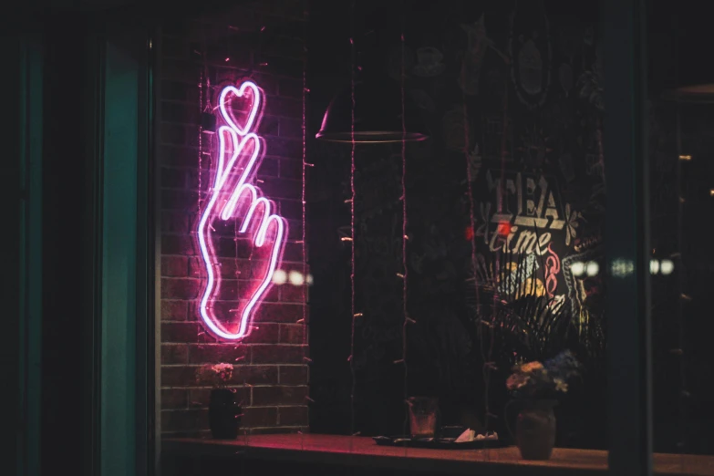 a neon sign that is on the side of a building, inspired by Elsa Bleda, trending on pexels, hand gestures, pink, small hipster coffee shop, middle finger