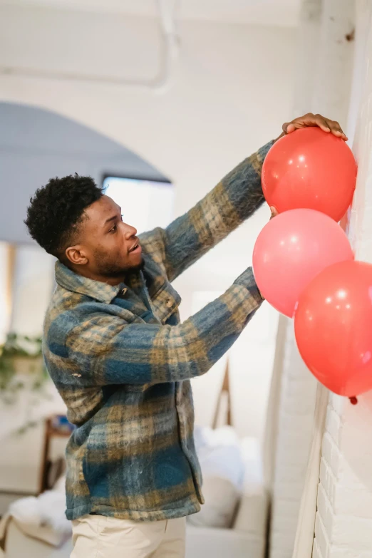 a man holding a bunch of red and pink balloons, by Jessie Algie, trending on pexels, happening, black teenage boy, creating a soft, decoration, jaylen brown