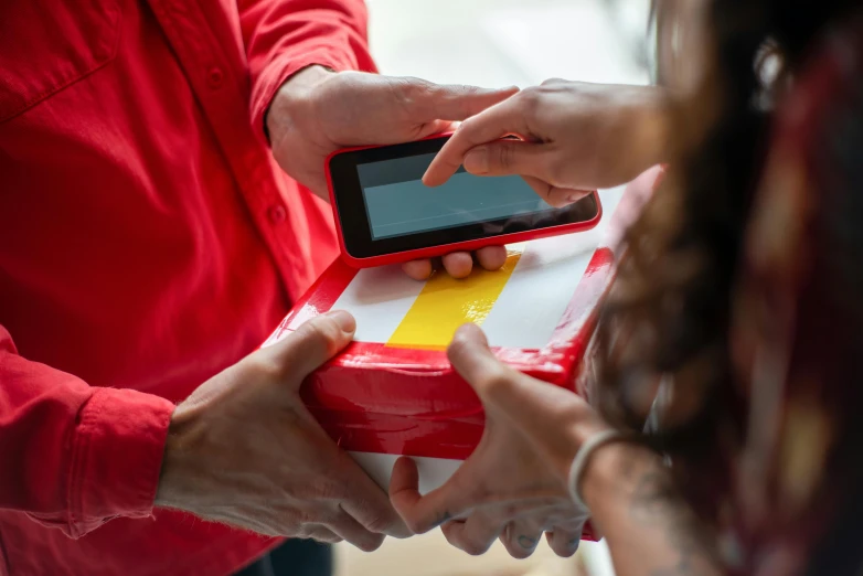 a close up of a person holding a cell phone, giving gifts to people, wearing red and yellow clothes, delivering mail, digital health