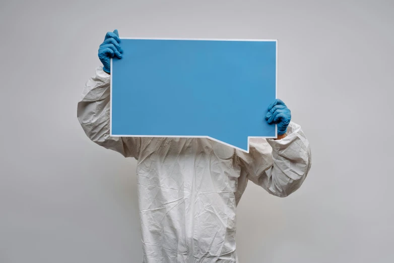 a person in a protective suit holding a blue sign, an album cover, by Paul Bird, pexels, plasticien, clean shapes, lab coat, large format picture, rectangle