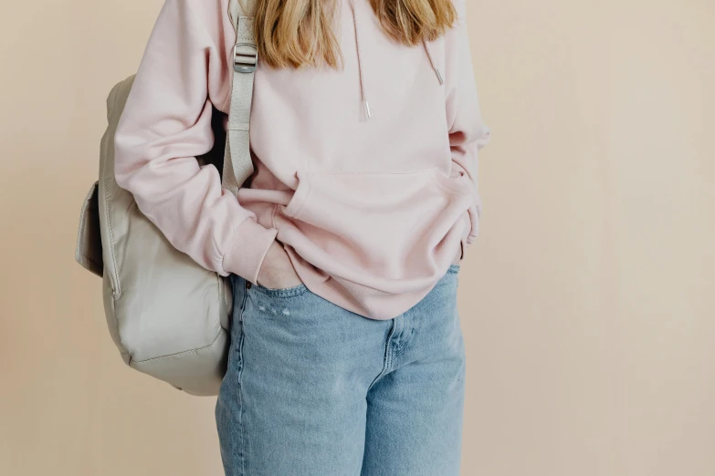 a woman wearing a pink hoodie and jeans, by Carey Morris, trending on pexels, minimalism, bags, pale colors, background image, gray hoodie