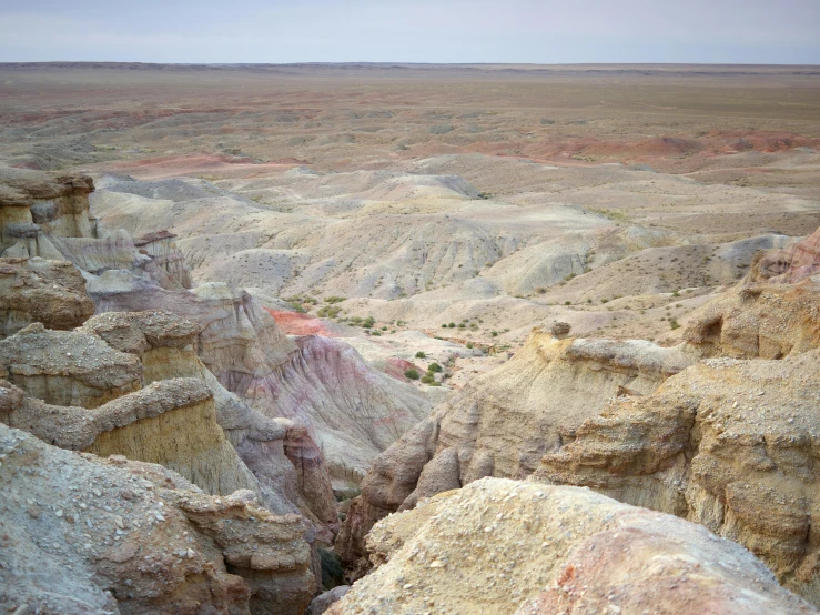 a large rock formation in the middle of a desert, a colorized photo, by Pamela Ascherson, unsplash, looking down on the view, west slav features, 2 5 6 x 2 5 6 pixels, multicoloured