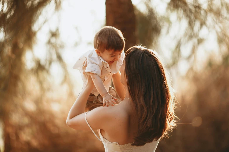 a woman holding a baby in her arms, pexels contest winner, sunlit, thumbnail, brunette, australian