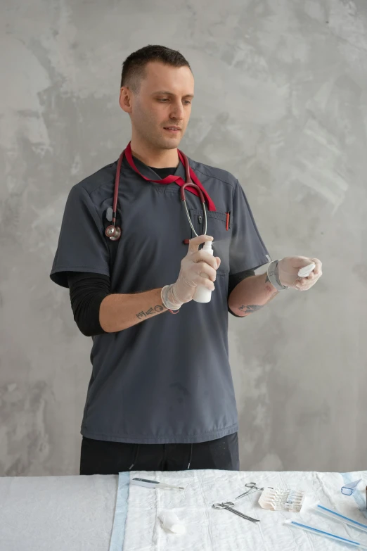 a man with a stethoscope standing in front of a table, wearing gloves, gray shirt, trending photo, official product image