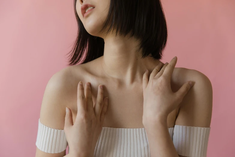 a woman standing in front of a pink wall, an album cover, inspired by Ren Hang, trending on pexels, aestheticism, muscular neck, kotegawa yui, open neck collar, flawless epidermis