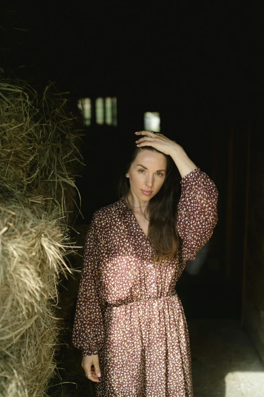 a woman standing next to a pile of hay, a portrait, unsplash, liv tyler, 35 mm photo, barn, wearing a long flowery dress