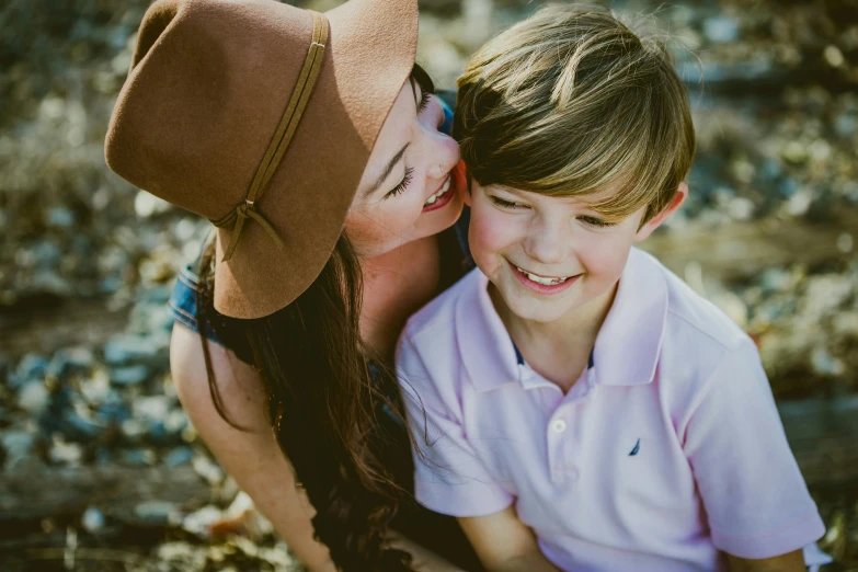 a woman sitting next to a boy with a hat on, pexels contest winner, happy girl, connor hibbs, thumbnail, close up shot from the top