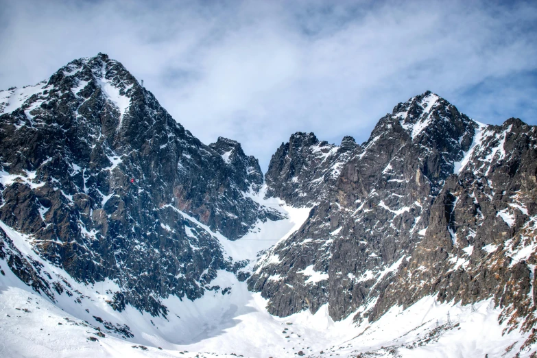 a group of people riding skis down a snow covered slope, pexels contest winner, les nabis, tall stone spires, large rocky mountain, larapi, panoramic