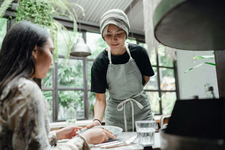 two women sitting at a table in a restaurant, pexels contest winner, wearing an apron, bangkuart, aussie baristas, gardening