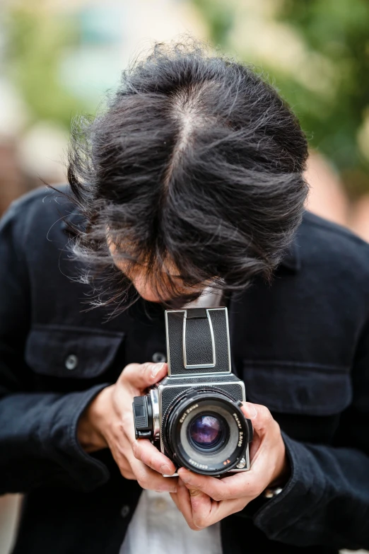 a person taking a picture with a camera, looking down on the camera, looking towards the camera