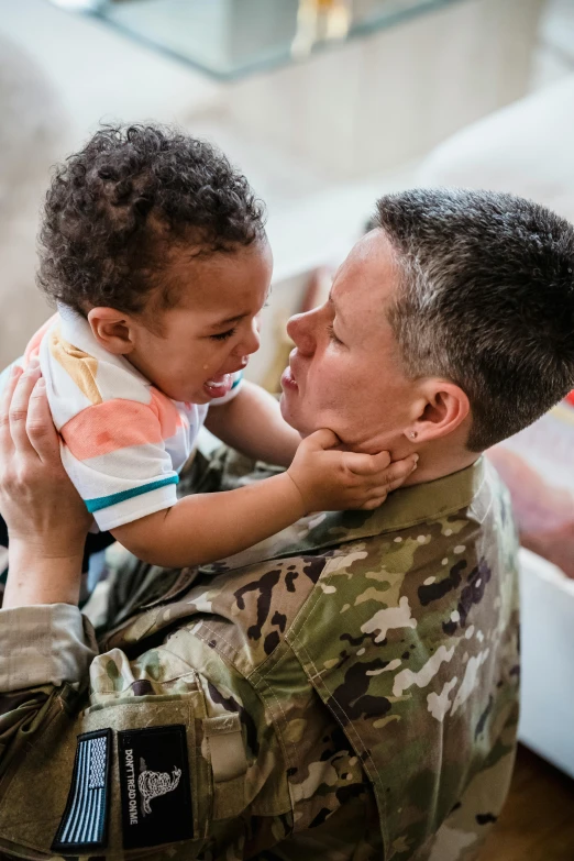 a soldier holding a small child in his arms, unsplash, transgender, square, united states air force, camouflage made of love