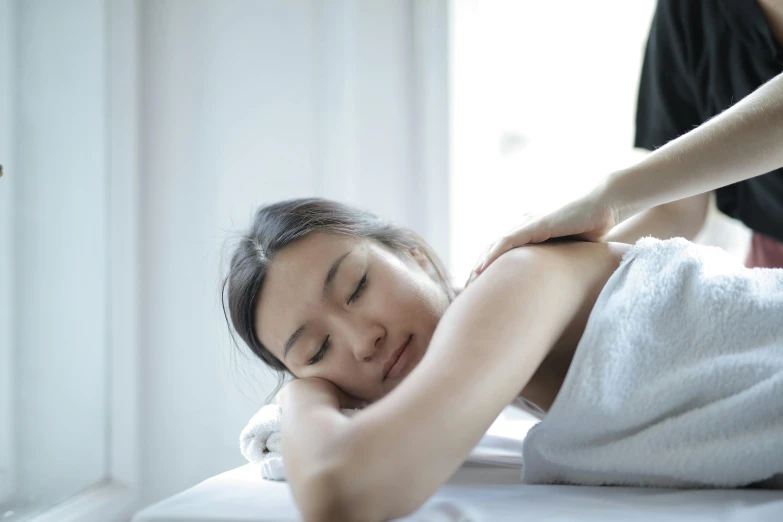 a woman getting a massage at a spa, a photo, by Alice Mason, pexels contest winner, with a white background, straya, soft light from the side, asian decent