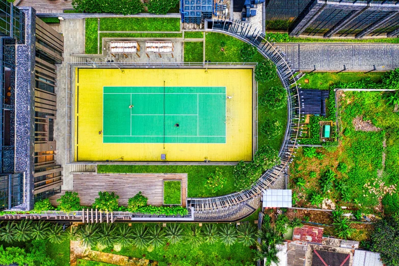 an aerial view of a tennis court surrounded by buildings, by Bernardino Mei, pexels contest winner, green and yellow, jakarta, roof garden, instagram post