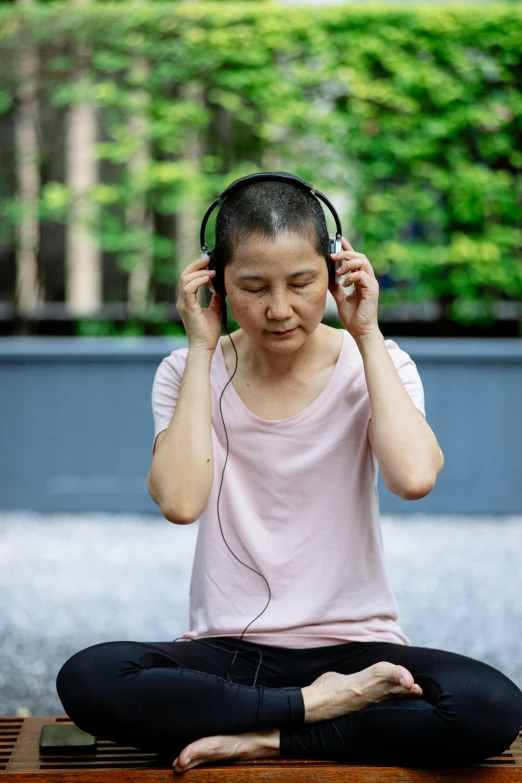 a woman sitting on a bench listening to headphones, inspired by Li Di, happening, hangzhou, meditating, wearing a headset, outside