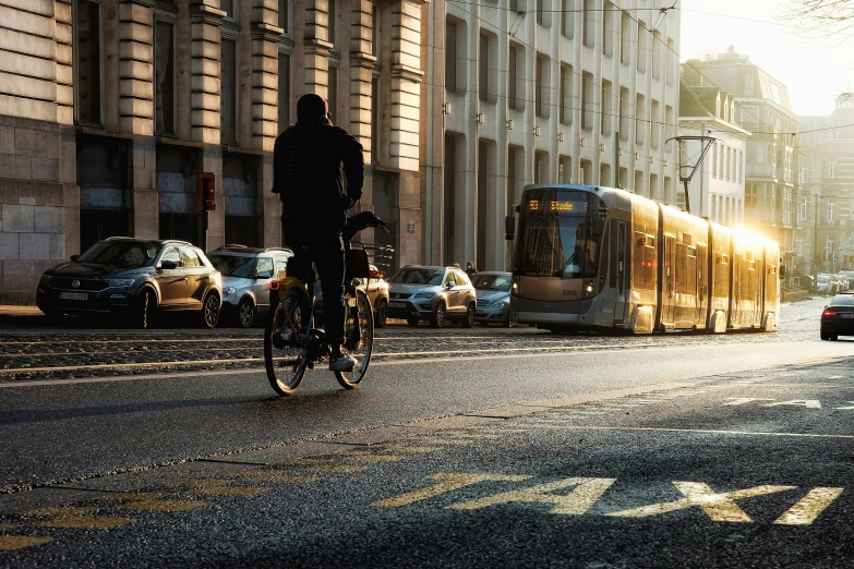 a person riding a bike on a city street, pexels contest winner, realism, sunny morning light, trams, olafur eliasson, north melbourne street