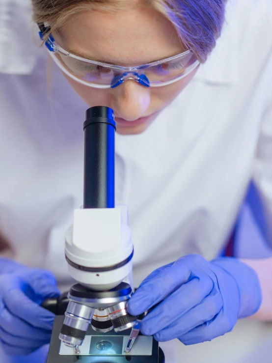 a woman in a lab coat looking through a microscope, a microscopic photo, shutterstock, thumbnail, enhanced quality, student, plating