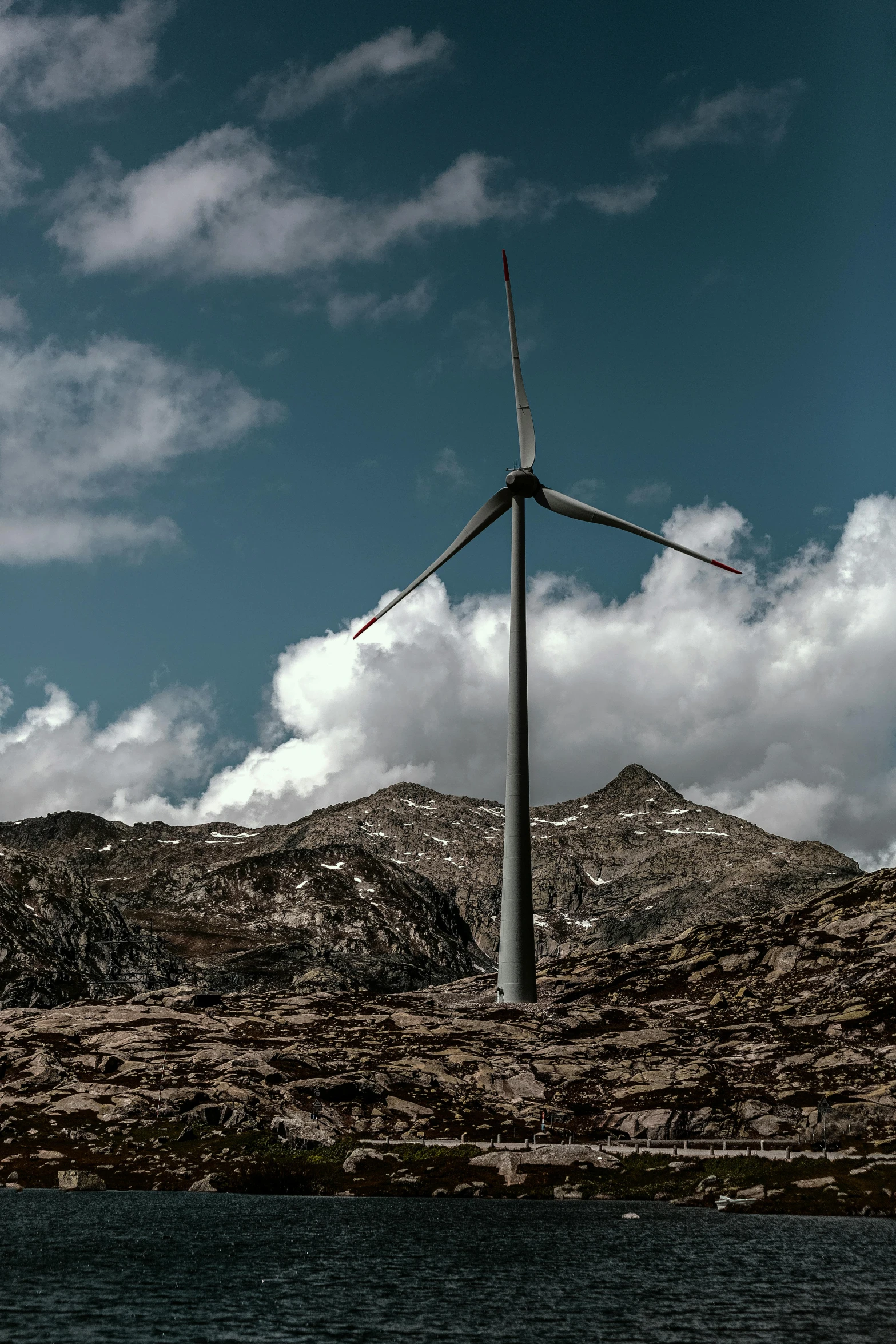 a wind turbine on top of a mountain next to a body of water, by Jesper Knudsen, pexels contest winner, renaissance, museum quality photo, highly detailed photo 4k, epic scale ultrawide angle, rustic