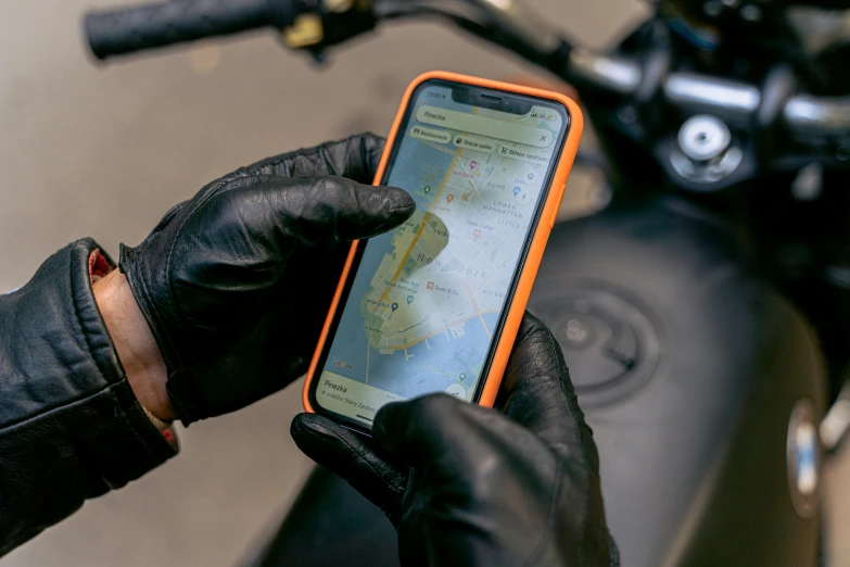 a close up of a person holding a cell phone, motorcycle, map, leather gloves, thumbnail